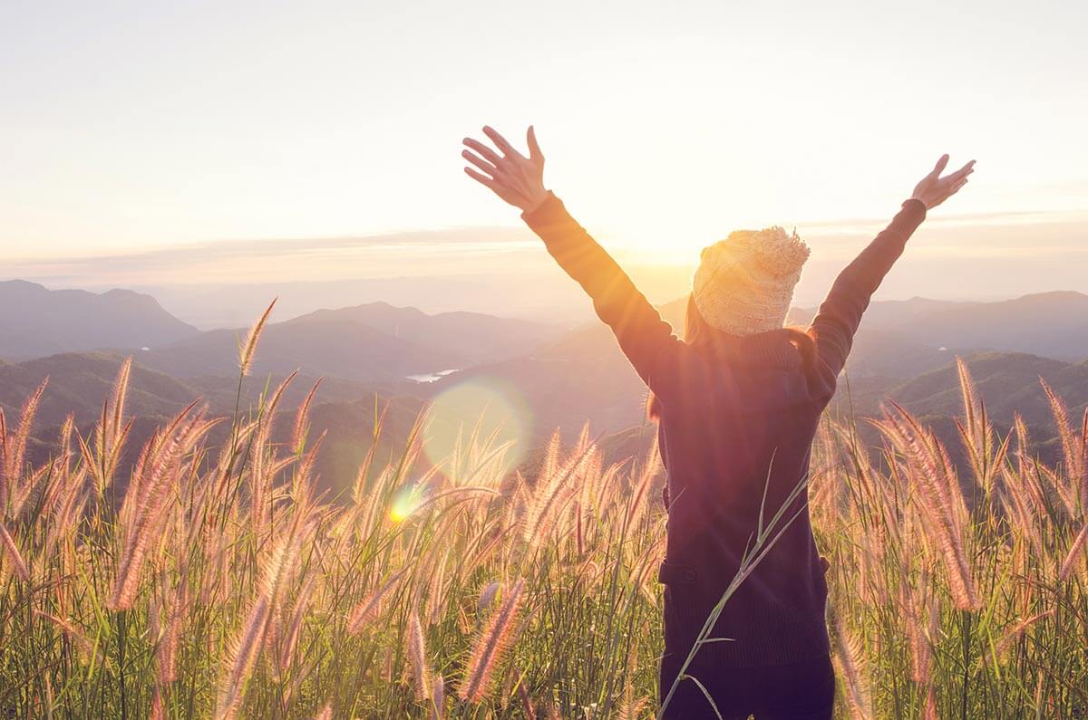 woman with arms outstretched freedom, sunset
